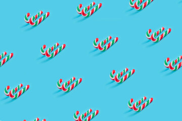 Pattern made of candy canes on pastel blue background.