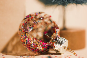 Broken Christmas tree toy, glitter ball, shards of glass on natural yellow background. Interior...