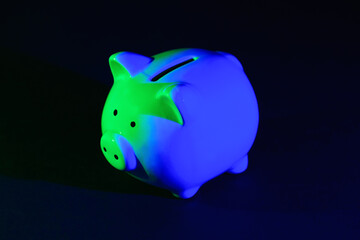 Piggy bank on a dark background with green-blue backlight. Banking concept. Bright neon lights on a black background