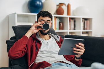 Man drinks coffee while looking at the tablet