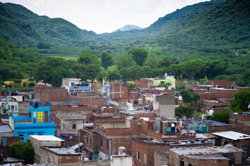aerial drone shot flying over small village rural town with concrete and brick buildings with green...