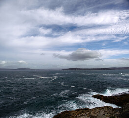 Stormy sea beats against the rocks against the background of a sky with clouds