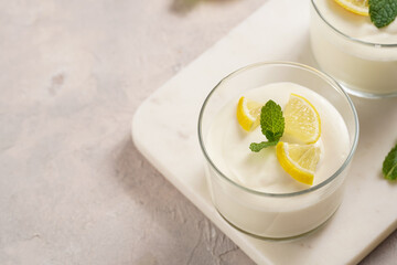 Creamy dairy yoghurt dessert sweet mousse with mascarpone, cream cheese, mint and lemon juice in glasses on marble tray