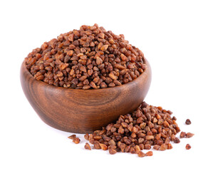 Buckwheat tea in wooden bowl, isolated on white background. Whole roasted buckwheat grains. Fagopyrum tataricum.