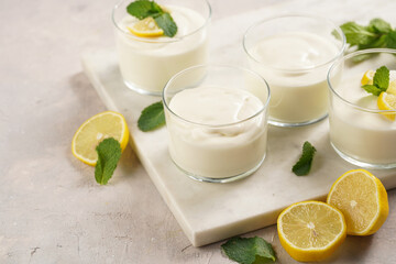 Creamy dairy yoghurt dessert sweet mousse with mascarpone, cream cheese, mint and lemon juice in glasses on marble tray