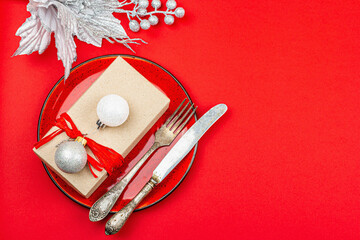 Christmas table setting with a festive gift box in red and silver colors. New Year background