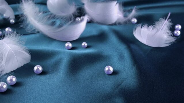 White swan feathers on blue silk with pearls.