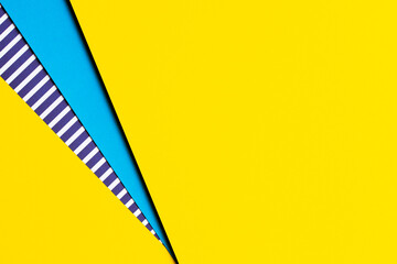 Abstract geometric bright colored papers texture background. Yellow background and blue, striped paper with blue and white stripes between. Top view, flat lay