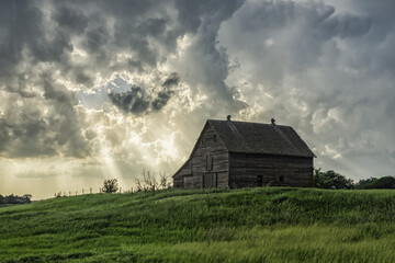 Abandoned barn with storm clouds converging overhead; Nebraska, United States of America
