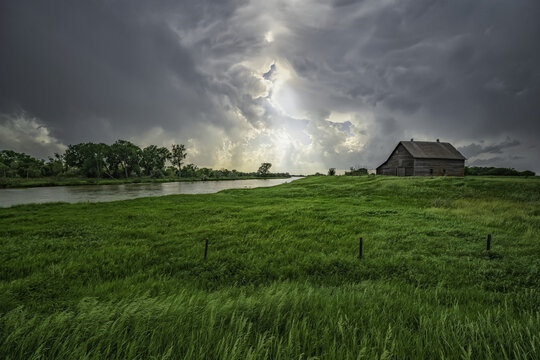 Abandoned barn with storm clouds converging overhead; Nebraska, United States of America