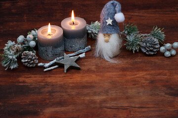 Rustic Advent and Christmas decoration: Two burning candles with fir branches and an elf. With...