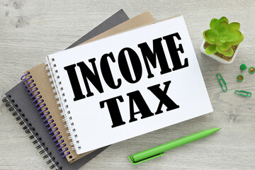Income and Tax text on notepad page wooden light background