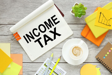 Income Tax text on a yellow notebook near a cup of coffee. Business concept