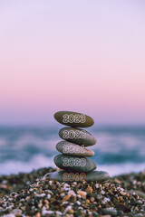 Selective Focus of pyramid of pebbles on the beach at sunset. Concept of the zen and happy new year 2023, stability, harmony, balance and meditation, copy space. 
