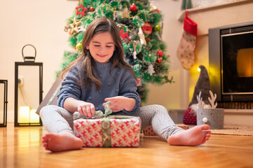 Cute girl opening christmas present. High quality photography.