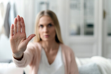 Woman showing stop gesture at camera, blurred background
