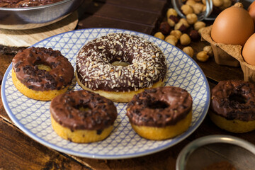 Preparing doughnuts at home. Ingredients for donuts such as eggs, milk, chocolate, pudding, butter, cacao, flour, rolling pin, cake pan, grater, egg beater, spatula