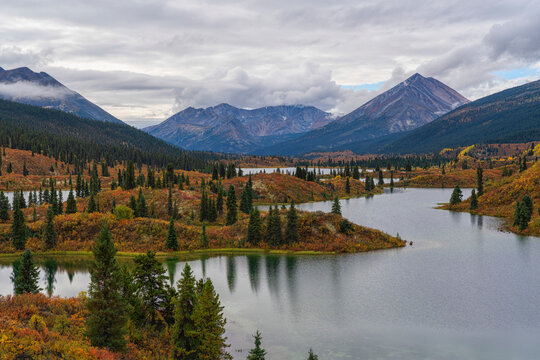 Rose Lake, Yukon with autumn colours on the hillsides; Ross River, Yukon, Canada