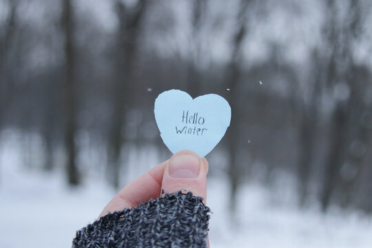 Hello Winter. Hand holds a blue heart with the inscription.