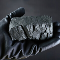 Hand holding black coal extracted from the mine.