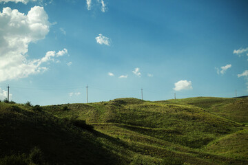 Beautiful minimalistic landscape, slope with lush green grass, blue sky with fluffy clouds, wallpaper