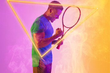 Fototapeta na wymiar Happy african american male tennis player holding racket shaking fist by illuminated triangle