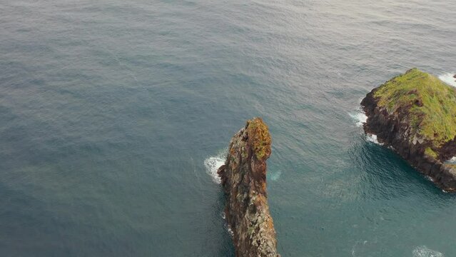 Aerial, orbit, drone footage of Ilheus da Rib costal arch, on Ribeira da Janela coast, foggy day, in Madeira, Portugal.