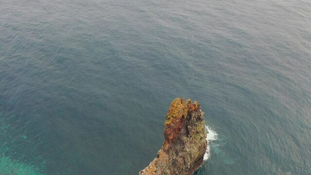 Aerial, orbit, drone footage of Ilheus da Rib costal arch, on Ribeira da Janela coast, foggy day, in Madeira, Portugal.