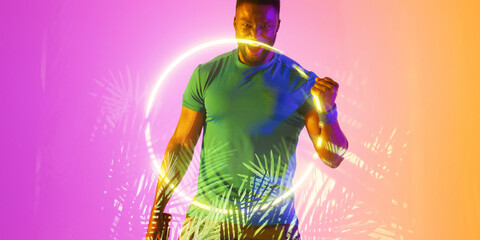 Cheerful african american male player screaming and shaking fist over illuminated circle and plants