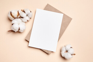 Holiday greeting card mockup with dried cotton flowers on beige background, top view, flat lay