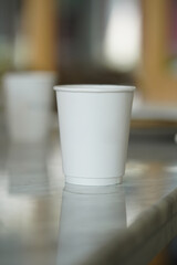 One white paper cup on a cafe table, a White cafe paper cup. 3d rendering, mockup.                 
