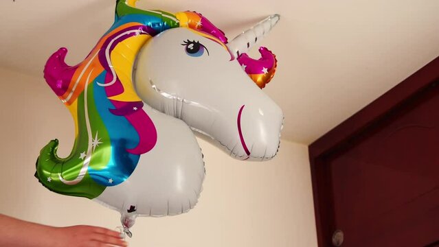 Hand taking a colorful unicorn balloon in room