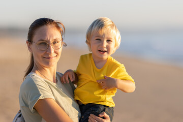 Smiling mother holding her little happy son on her hands