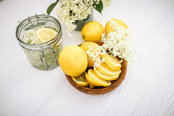 A wooden plate with fresh lemons for a healthy refreshing non-alcoholic lemonade with syrup from...