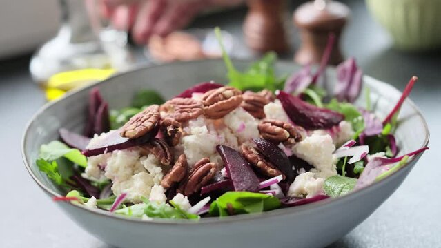 Salad making video 4k. Fresh nutrition salad of beetroot, babyspinat, onions, rukkola, pecan and white soft cheese. Homemade cooking footage.