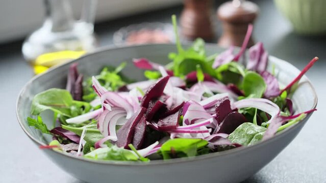 Salad making video 4k. Fresh nutrition salad of beetroot, babyspinat, onions, rukkola, pecan and white soft cheese. Homemade cooking footage.