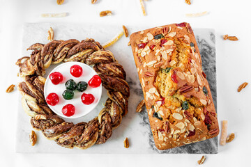 Close up de pan de frutas con cerezas acompañado de una rosca de chocolate.