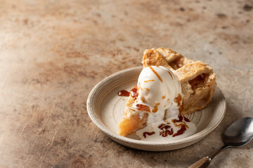 Slice of traditional apple pie with ice cream on brown textured background, menu, text space