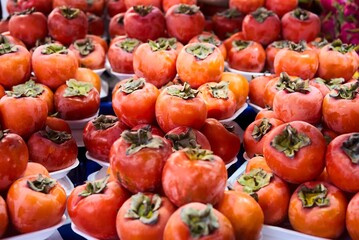 Fresh ripe persimmons in market. Persimmons background. Organic persimmon fruit in pile at local farmers market. Persimmons background. Close-up . High quality photo