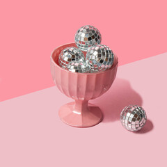 Christmas baubles in ice cream bowl on pastel light pink background. Minimalistic New Year concept. Christmas flat lay. Creative Xmas composition.