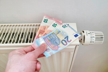 Energy efficiency concept with radiator and euro currency &ndash; the cost of thermal energy is more expensive due to global energy crisis. Selective focus.