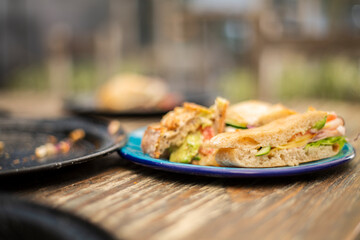 Emparedado de 
en mesa de madera con un plato negro.