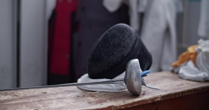 Fencing mask and foil on bench
