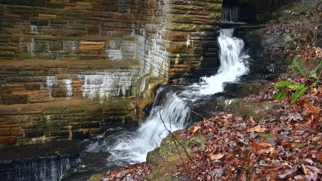 A small initial spillway on Byrd Creek Dam in Cumberland Mountain Tennessee shows the fall colors and brick details of the dam as the water flows down to the river below.