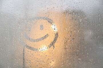 Happy face drawn on foggy window, space for text. Rainy weather