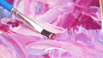 Applying colorful oil paints with brush on canvas, closeup