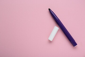 Bright purple marker and cap on light pink background, flat lay. Space for text