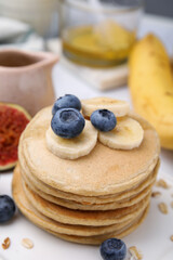 Tasty oatmeal pancakes with fruits on plate, closeup