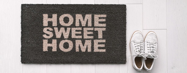 Home entrance mat with shoes. Doormat of new homeowner moving to new house at entrance for welcome...