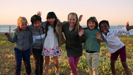 Children, group and waving while playing during summer and having fun in nature with joy. Carefree, diverse boys and girls with friends or mates hugging and embracing with affection and freedom - Powered by Adobe